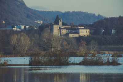 Houses by lake and buildings against mountain