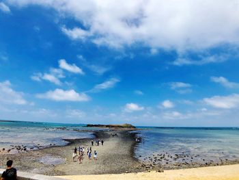 Group of people on beach against sky