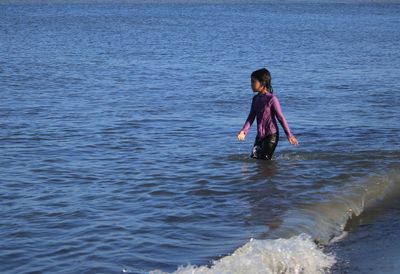 Full length of young woman standing in sea