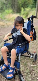 Full length of young child sitting in buggy stroller on the field