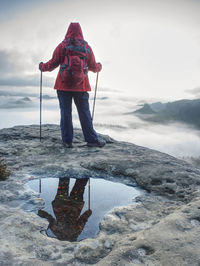 Woman hiker on extreme trail in rocks enjoy amazing view into misty valley. hiker enjoy silent rocks