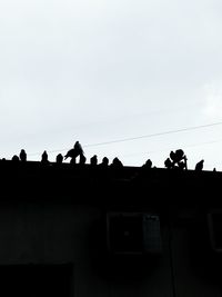 Silhouette people on building terrace against clear sky