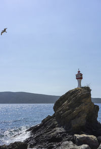 Lighthouse by sea against sky