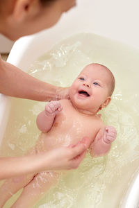 High angle view of woman giving bath to toddler in bathtub