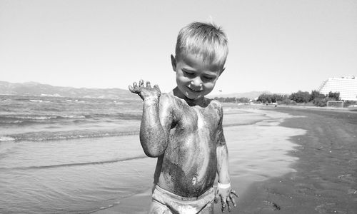 Little boy covered in sand at the beach