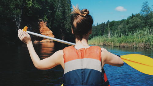 Rear view of woman paddling canoe in lake