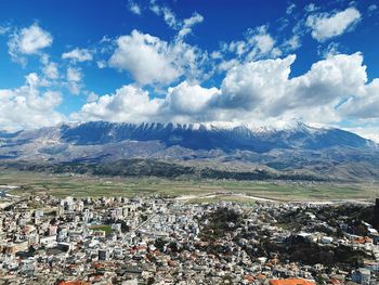 Aerial view of town by mountains against sky