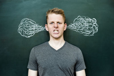 Portrait of angry man with drawing on blackboard
