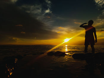 Silhouette people on beach against sky during sunset