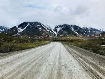 Road amidst snowcapped mountains against sky