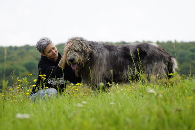 Young man with horse on field against sky