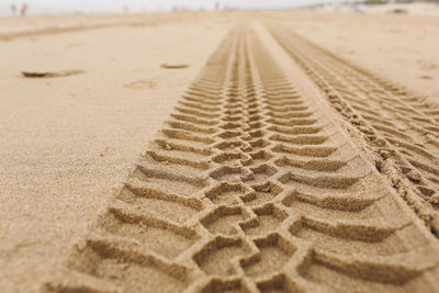 Close-up of tire tracks at sandy beach