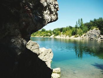 Rock formation by lake against sky