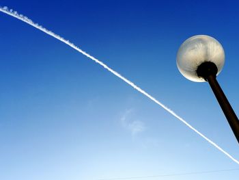 Low angle view of vapor trails against blue sky