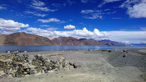 Scenic view of lake by mountains against blue sky
