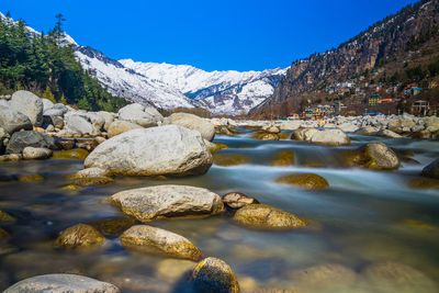 Scenic view of river by mountains against clear sky