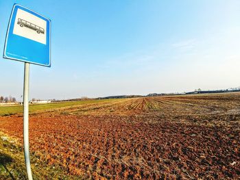 Road sign on field against sky