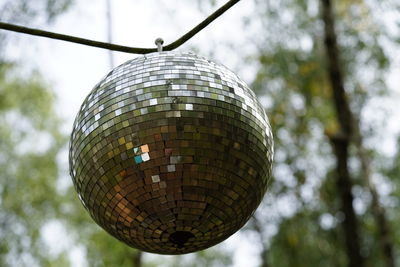 Low angle view of disco ball hanging from tree