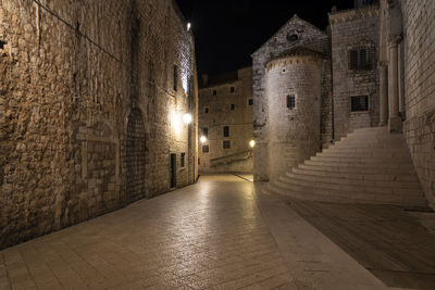 Alley amidst buildings in city at night