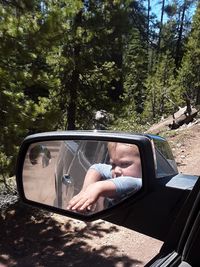 Reflection of baby boy on side-view mirror