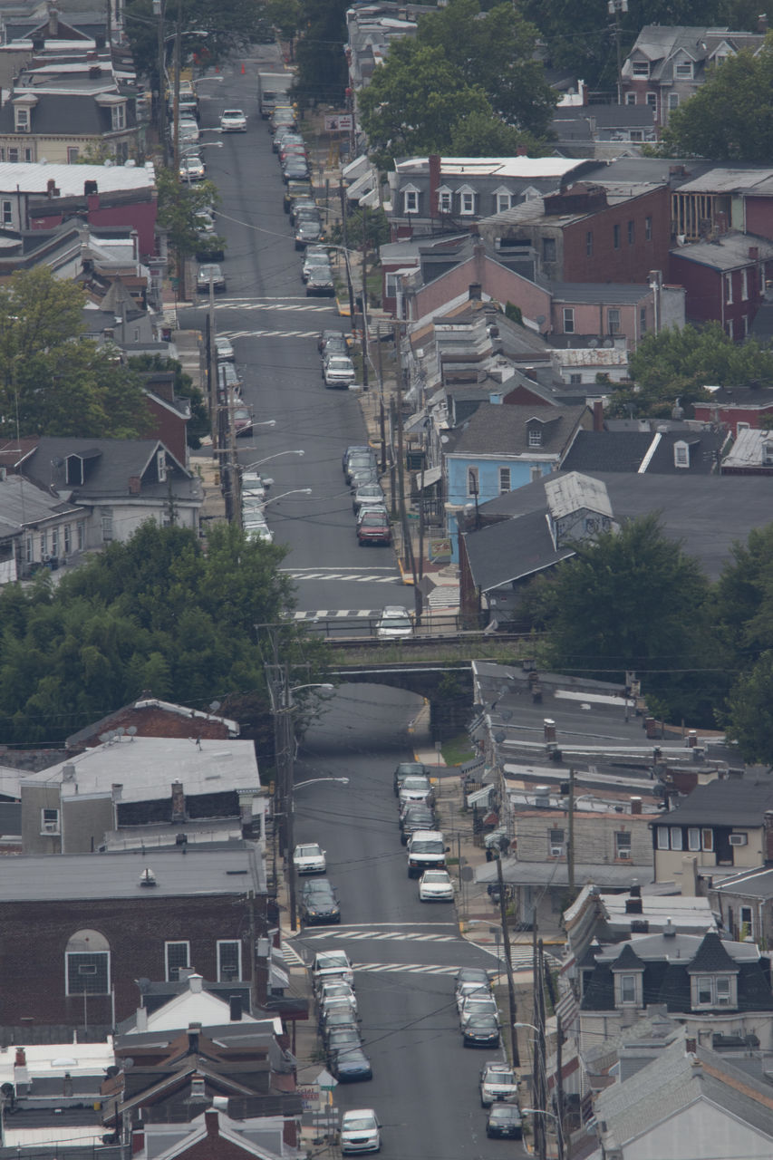 HIGH ANGLE VIEW OF CARS ON STREET AMIDST BUILDINGS IN CITY