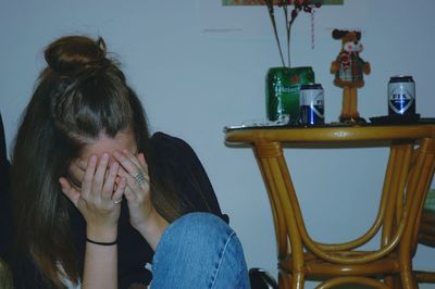 Woman covering face while sitting at home