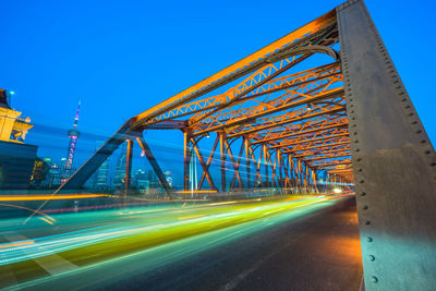 Light trails on bridge in city against clear blue sky