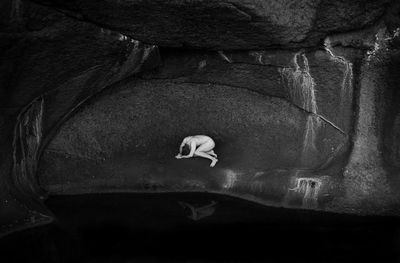 Naked man lying down in cave