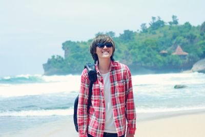 Portrait of young woman standing against sea