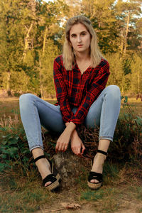 Portrait of beautiful young woman sitting on land