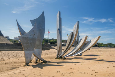 Deck chairs on beach against sky