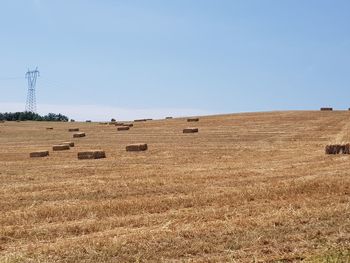 Hay bales on field against clear sky