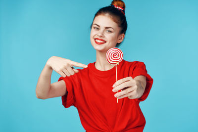 Portrait of smiling young woman against blue background