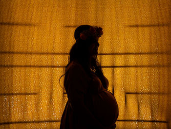 Side view of woman standing against wall