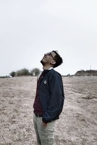 Side view of boy standing at beach against clear sky. he just trying to share a laugh.