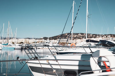 Sailboats moored at harbor against clear sky