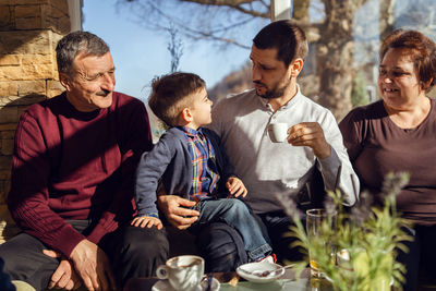Grandparents looking at son talking to grandson at home
