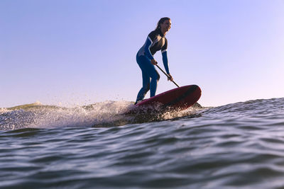 Female sup surfer at sunset time