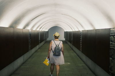 Rear view of woman walking in tunnel