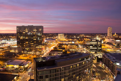 Illuminated cityscape against sky at dusk