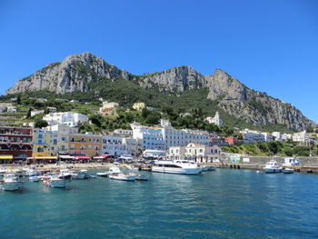 Sailboats moored in sea against clear blue sky