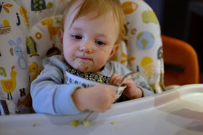 Adorable little baby girl sitting in high chair and eating