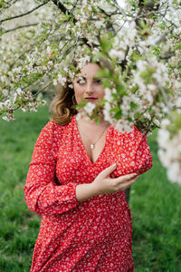 Midsection of woman standing by red flowering plants