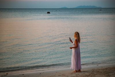 Woman standing on beach against sea