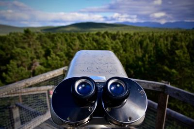 Coin-operated binoculars by landscape against sky