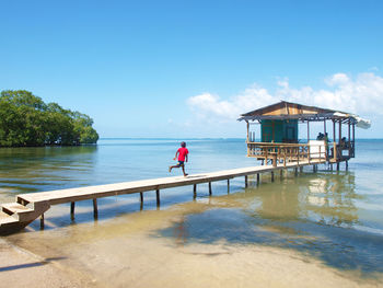 Man standing on pier by sea against sky