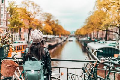 Woman standing on footbridge over canal in city