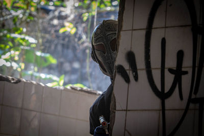 Portrait of man standing against graffiti wall