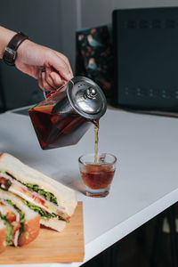 Hand pouring tea in cup on table