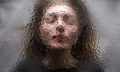 Close-up of woman seen through wet glass